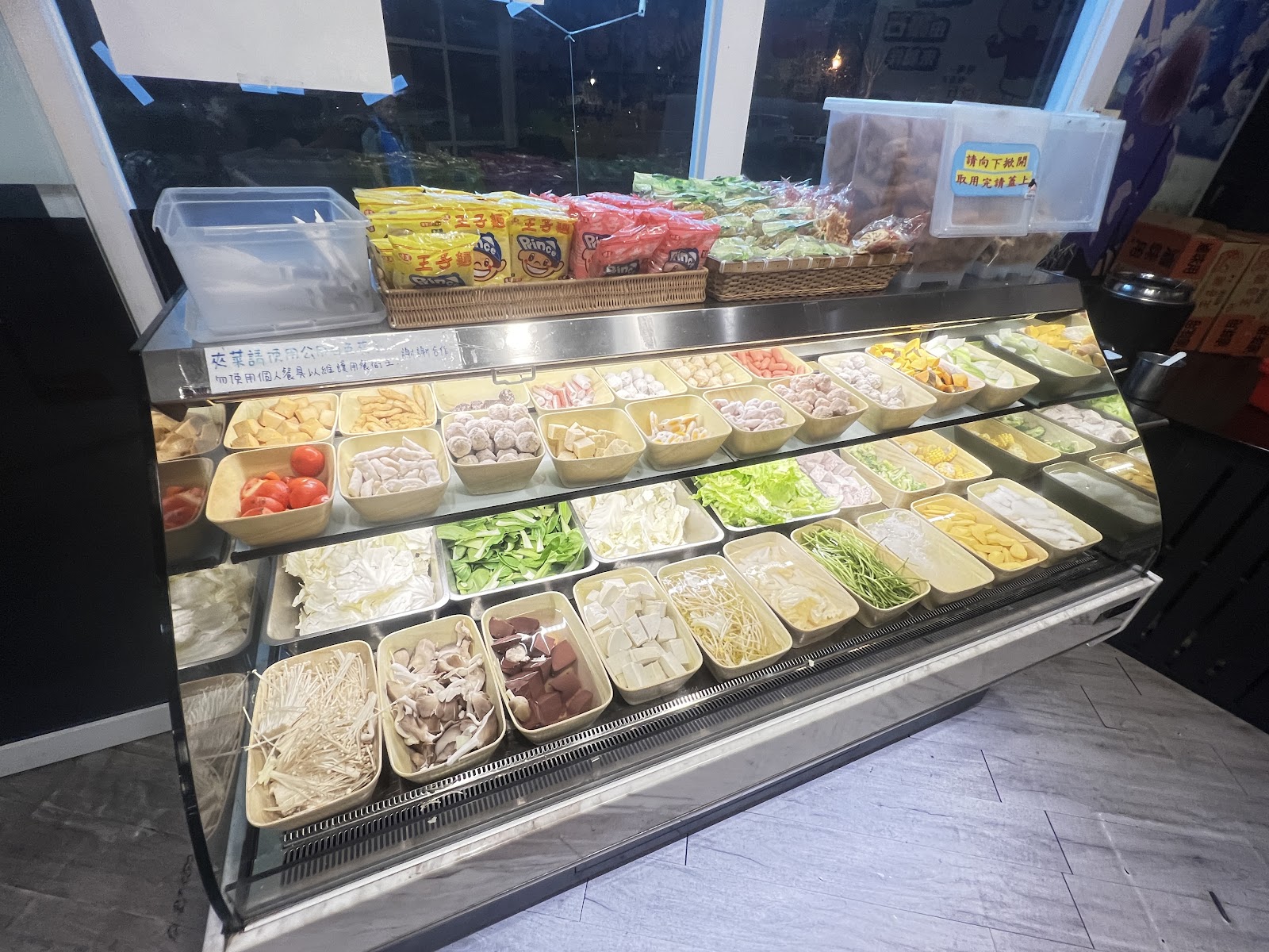 誠石火鍋岡山店豐盛自助蔬菜吧全景，玻璃冷藏展示櫃擺滿各種火鍋食材