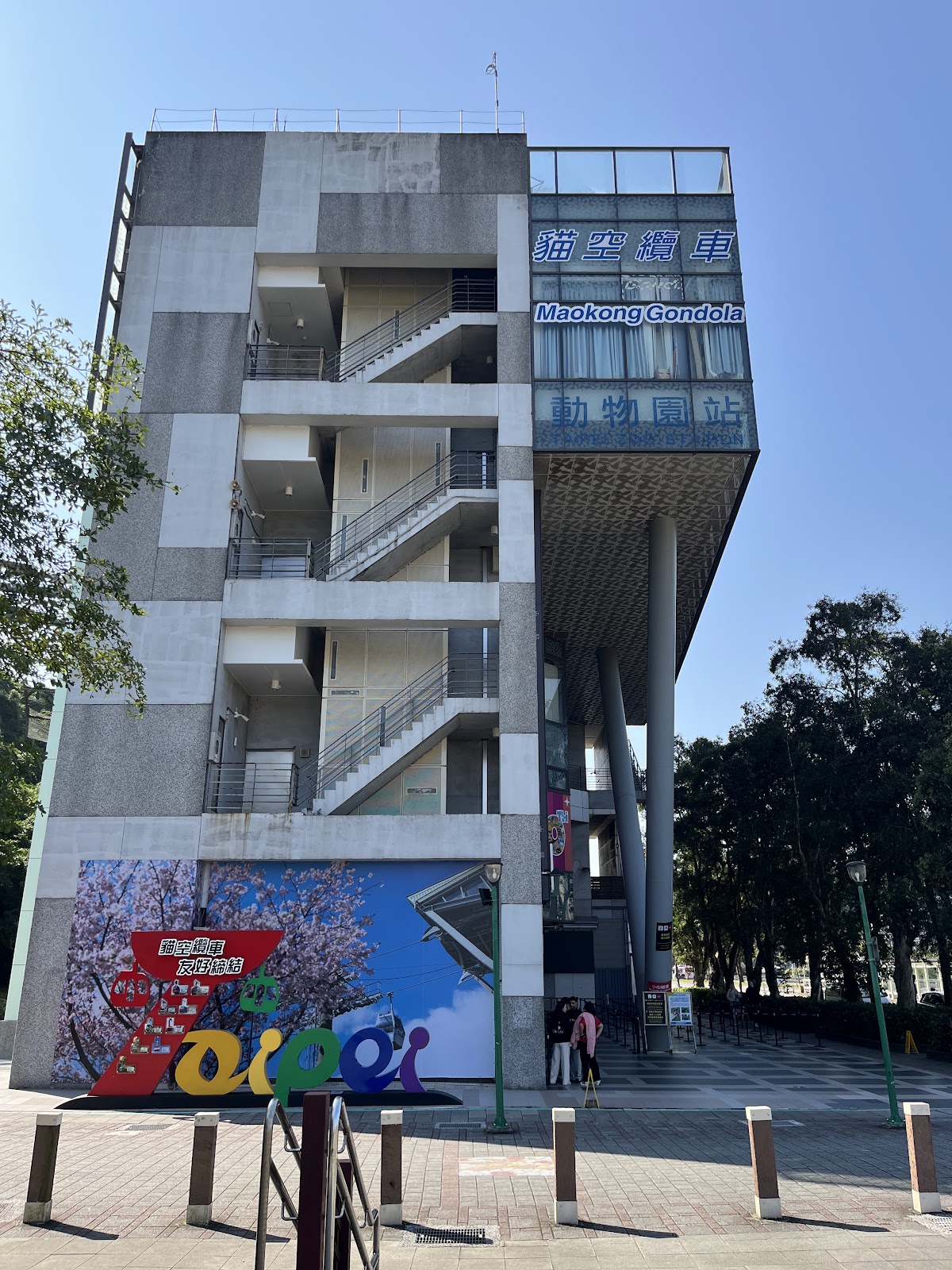 貓空纜車動物園站建築全景豎拍，晴天藍天，站名招牌清晰可見