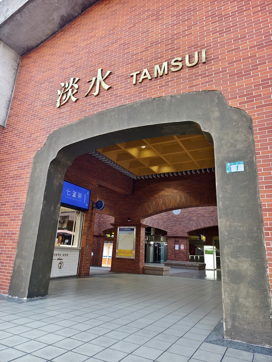 淡水捷運站入口拱形紅磚外觀，正面寫著淡水老街交通指引