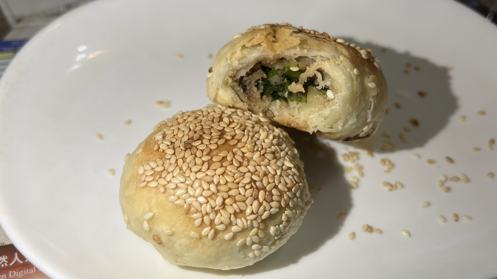 五結阿賢碳烤燒餅剖面，金黃酥皮芝麻撒頂，露出蔥肉餡料