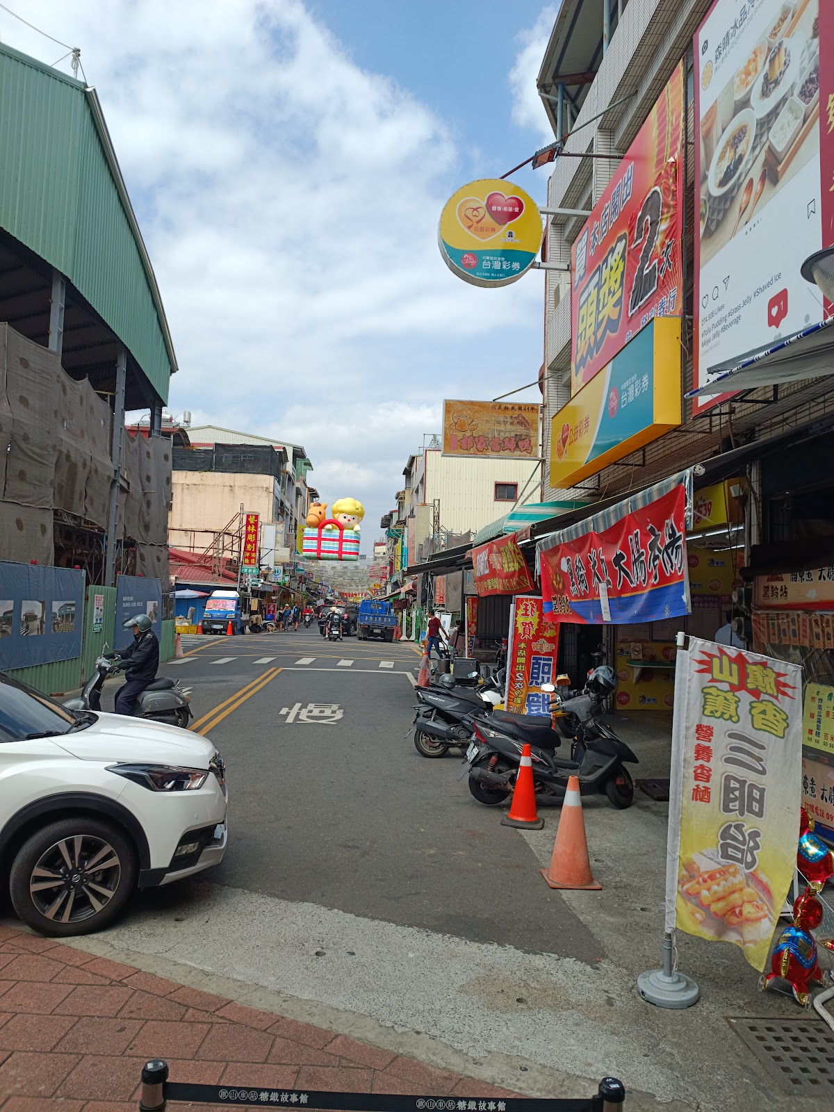 旗山老街街道縱深，路邊攤販招牌林立，遠處老街拱門