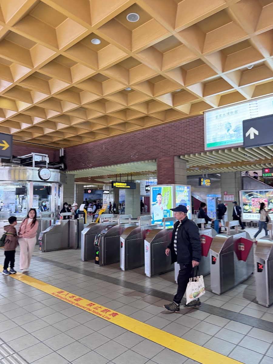 淡水捷運站內部，蜂巢格子天花板，旅客走過剪票口，前往淡水老街