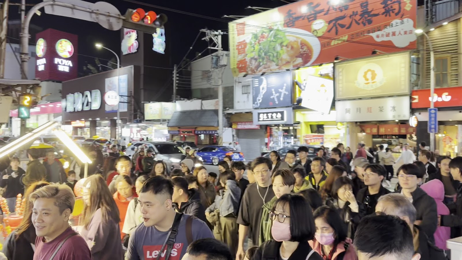 逢甲夜市街口夜晚人潮洶湧，兩側商店招牌燈火通明
