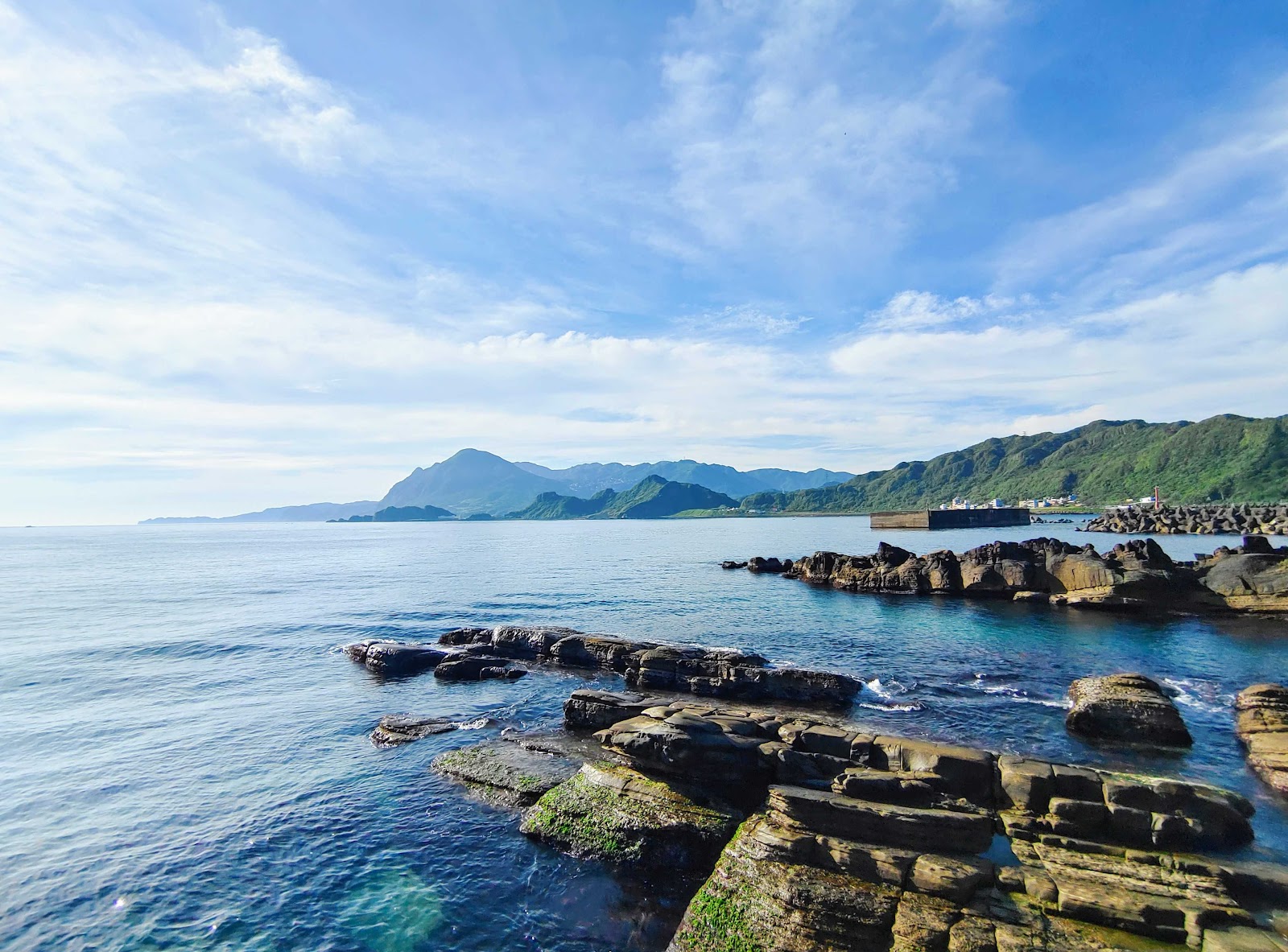潮境公園崎嶇岩岸，礁岩點綴翠綠植披，蔚藍大海延伸至遠方