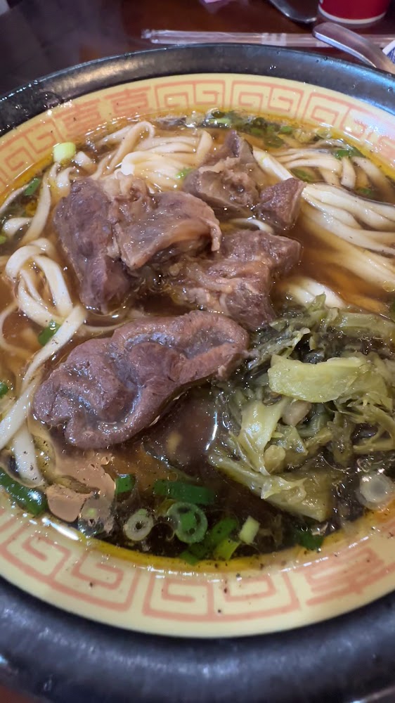 牛肉麵近拍，粗麵條搭配大片牛肉與酸菜