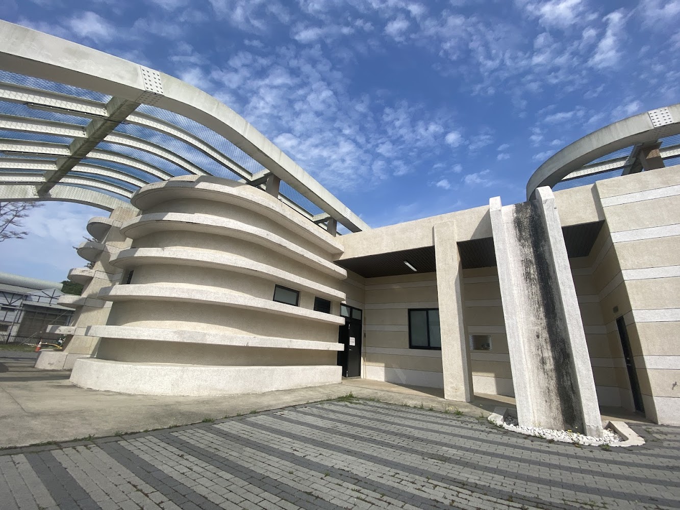 一棟造型獨特的現代建築，屋頂有曲線鐵架結構，建築外牆有層疊設計。