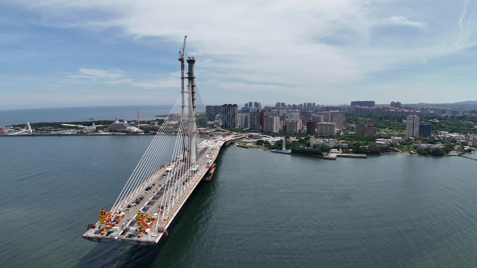 淡江大橋施工空拍圖，橋面橫跨淡水河，橋塔雄偉，背景淡水市區