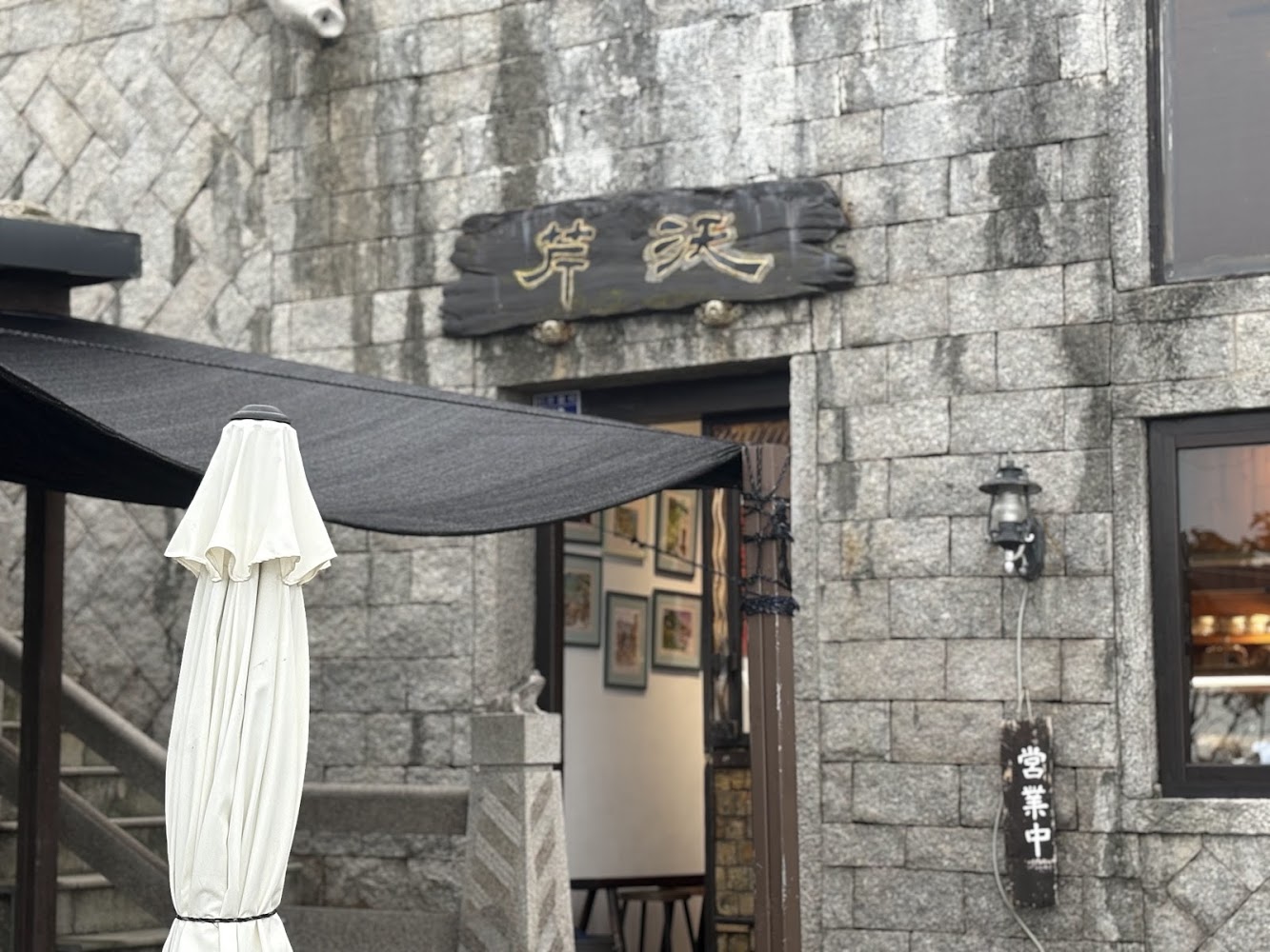 以石頭磚牆建造的芹沃咖啡烘焙館外觀，門口掛著營業中告示