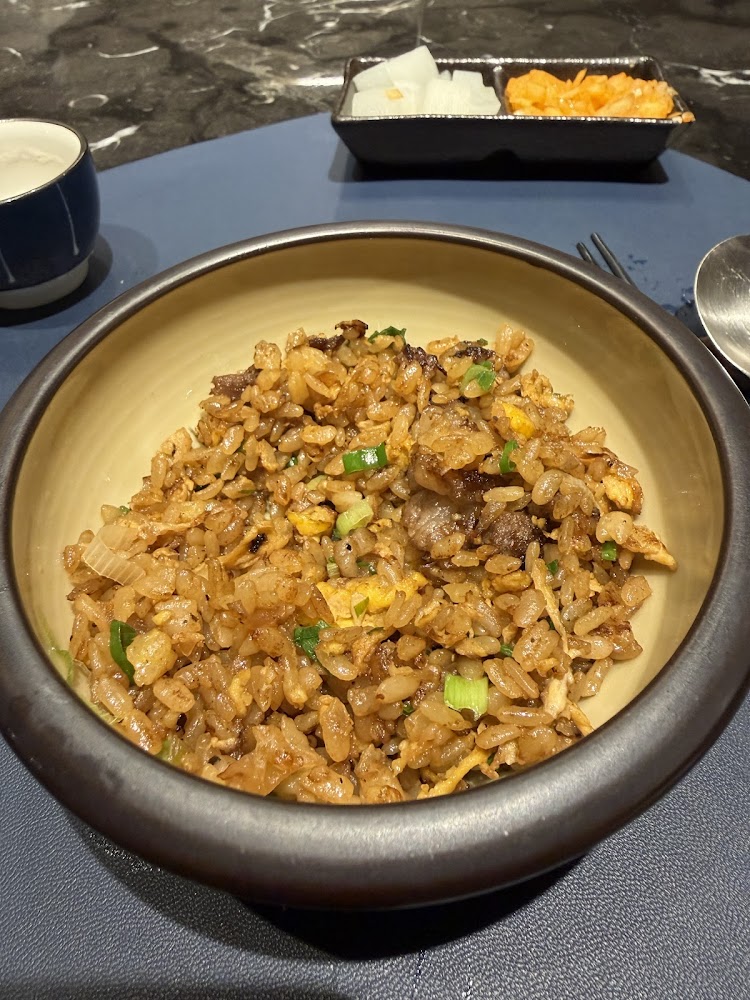 一碗炒飯，裡面有米飯、蛋、蔥與肉丁，旁邊有泡菜與白蘿蔔