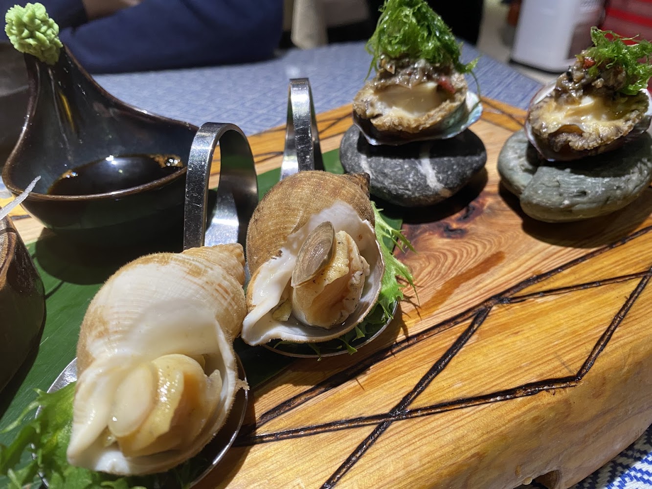 擺盤精美的貝類與鮑魚海鮮料理旁附醬油與芥末