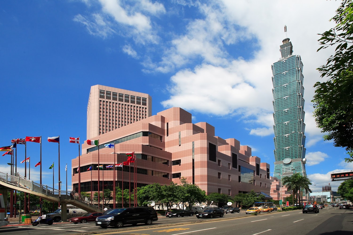 台北101與TICC周邊街景同框，前方有道路與旗幟。