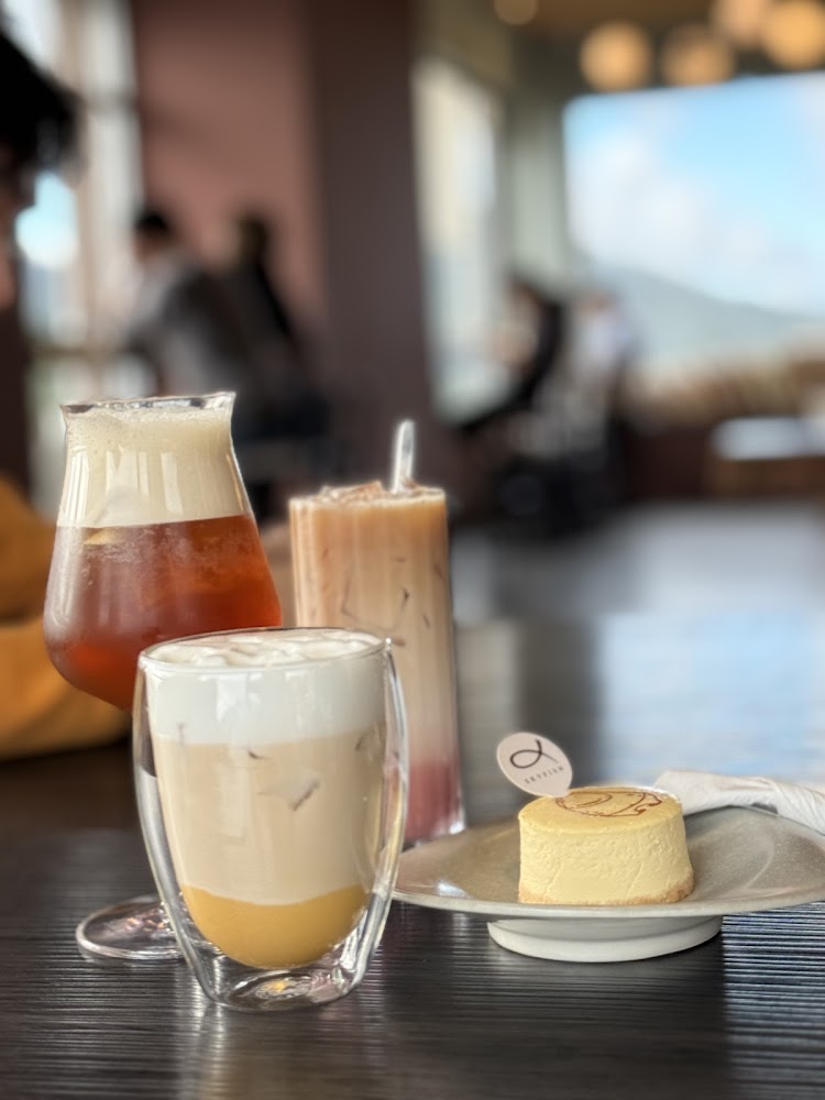三杯不同飲品與起司蛋糕擺放在木桌上