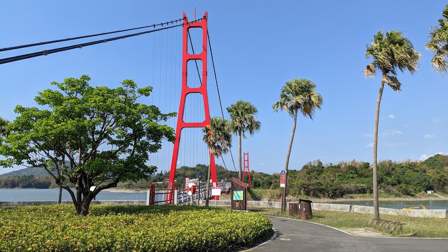紅色吊橋與綠樹河岸景觀