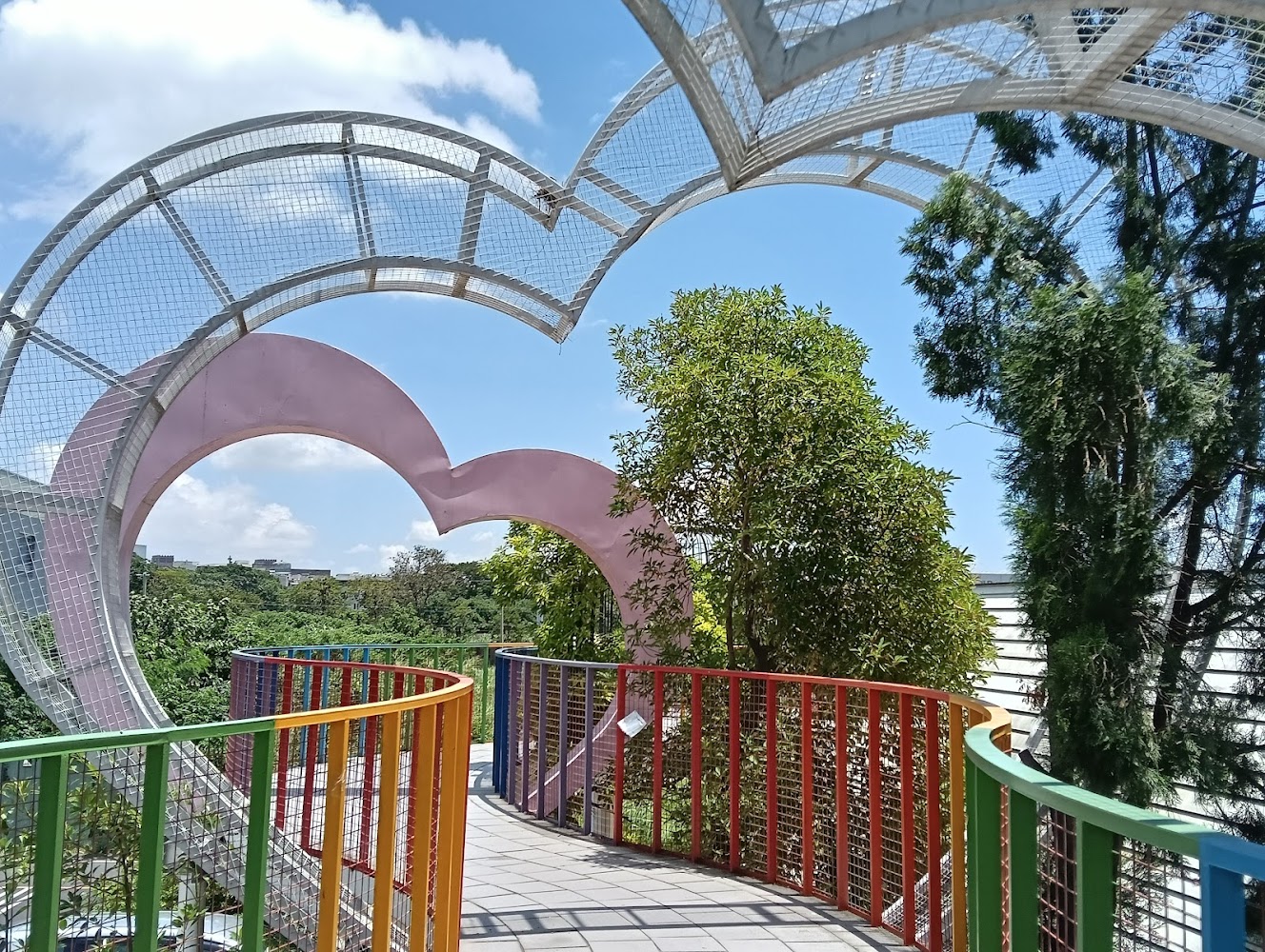 彩虹欄杆空中步道，上方有心形拱門，周圍綠樹環繞