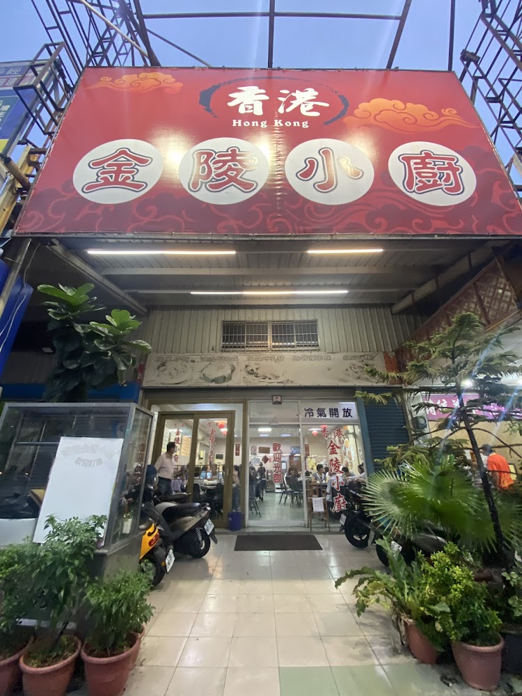 香港金陵小廚餐廳門口，有紅色招牌與多盆綠植，門口停著幾台機車