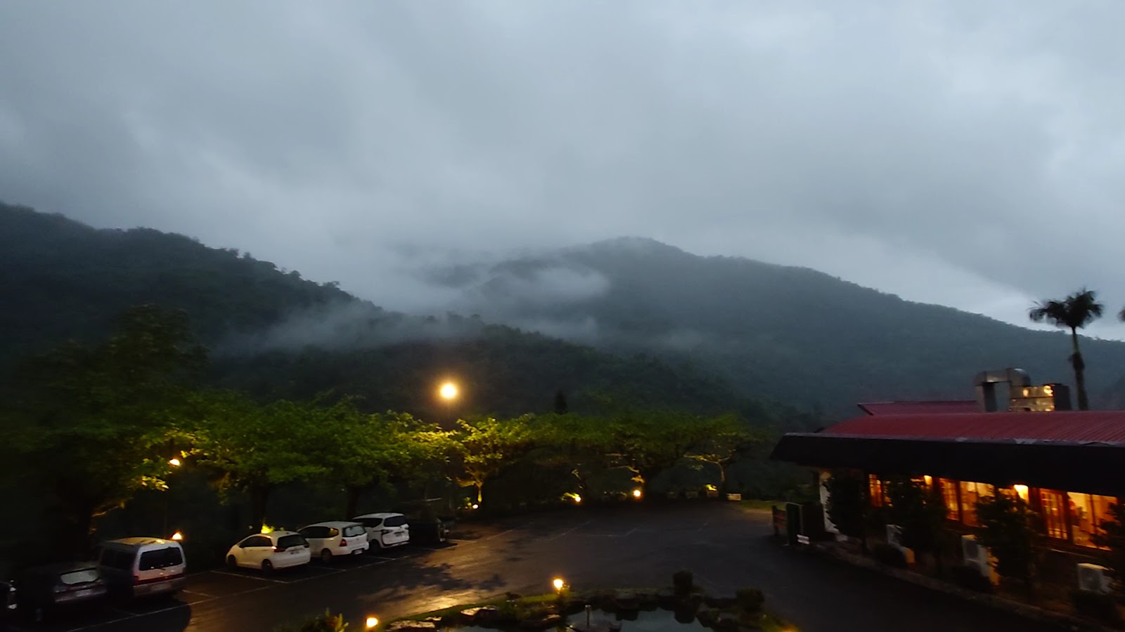 台東知本泓泉溫泉渡假村停車場夜景，濃霧山頭橘黃路燈點亮紅頂建築