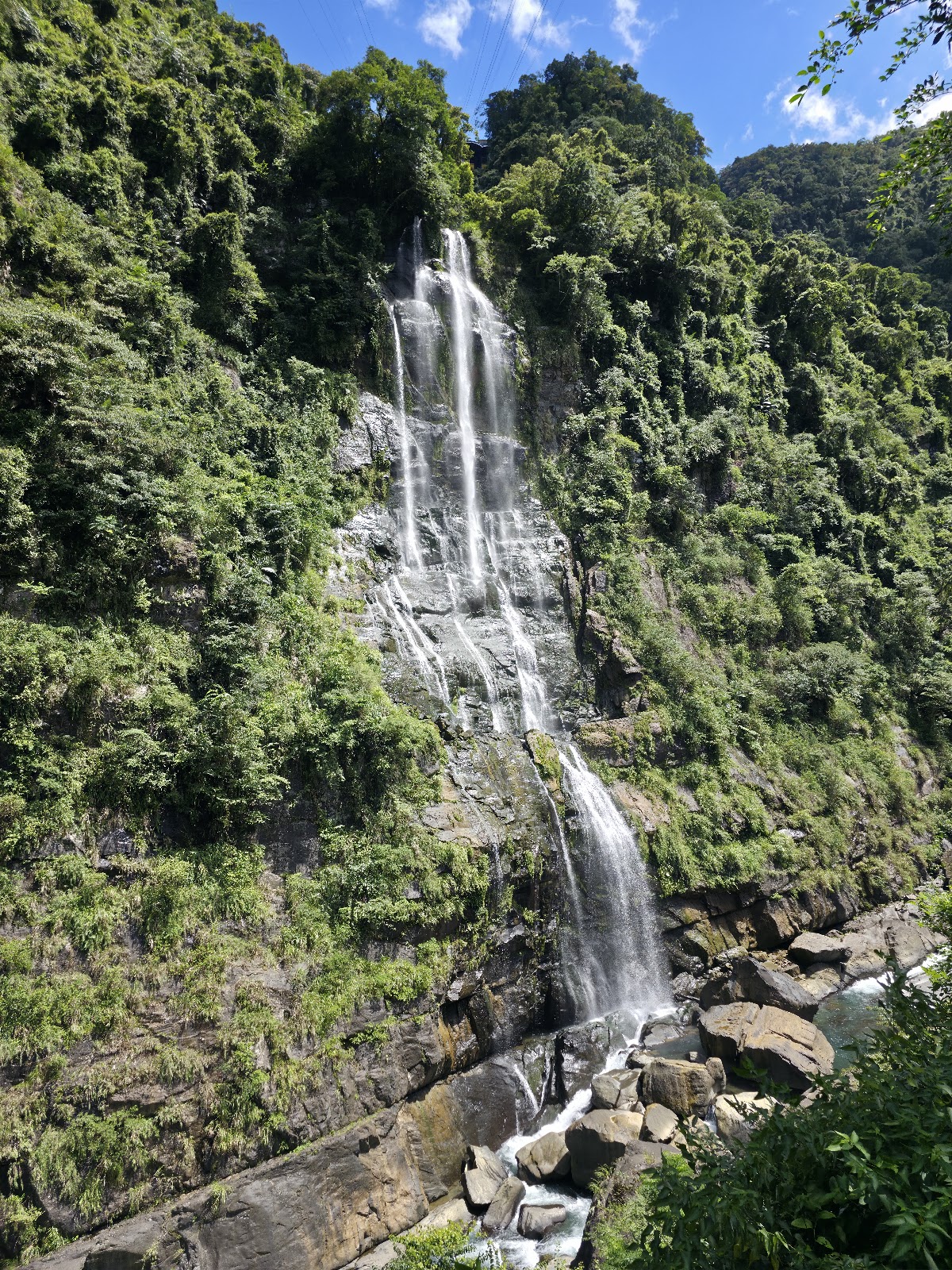 烏來瀑布全景，白色水流從翠綠山壁直瀉而下，氣勢磅礴