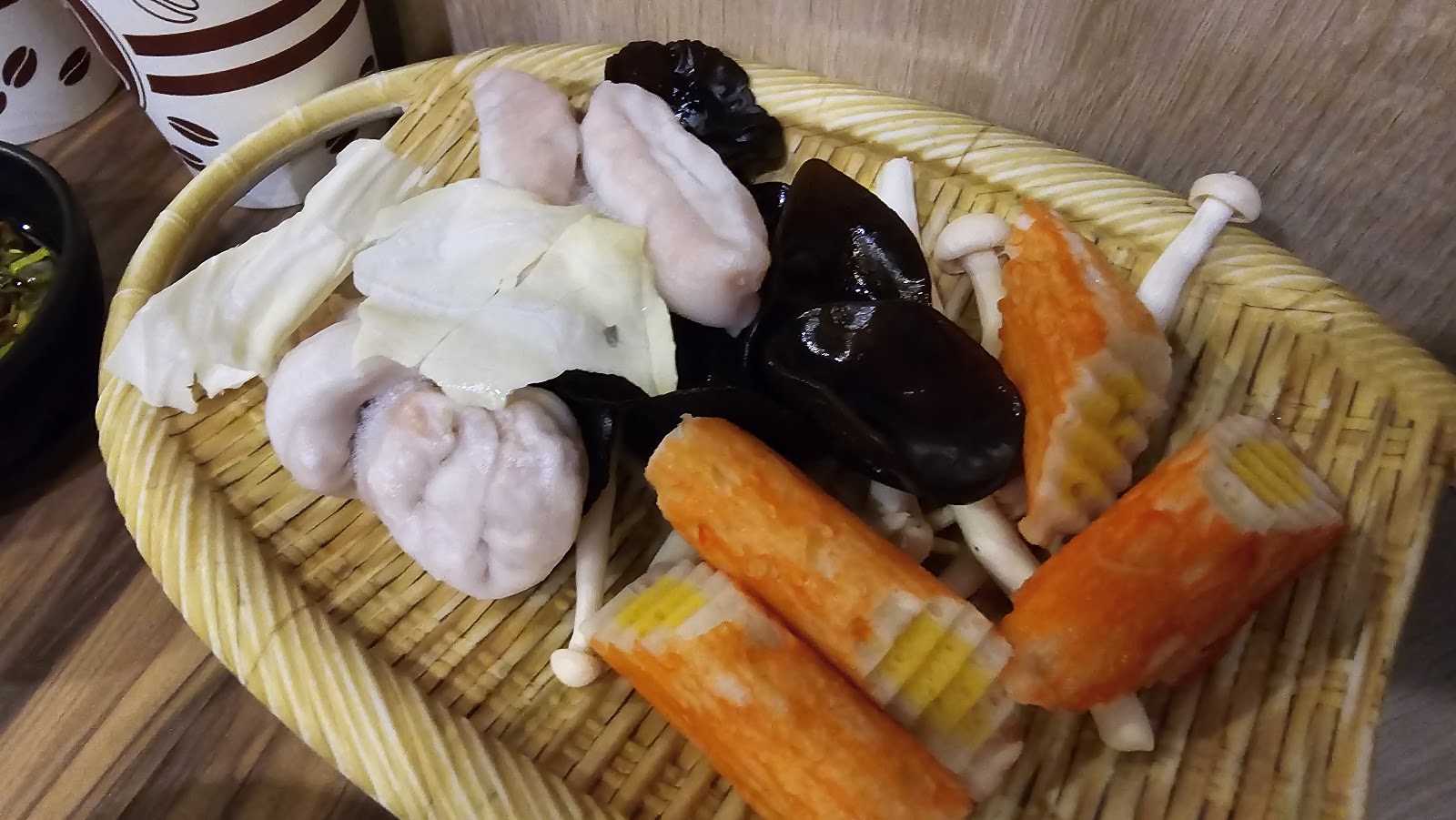 誠石火鍋岡山店竹籃盛放火鍋料，蝦餃黑木耳蟹肉棒蘑菇排列精美
