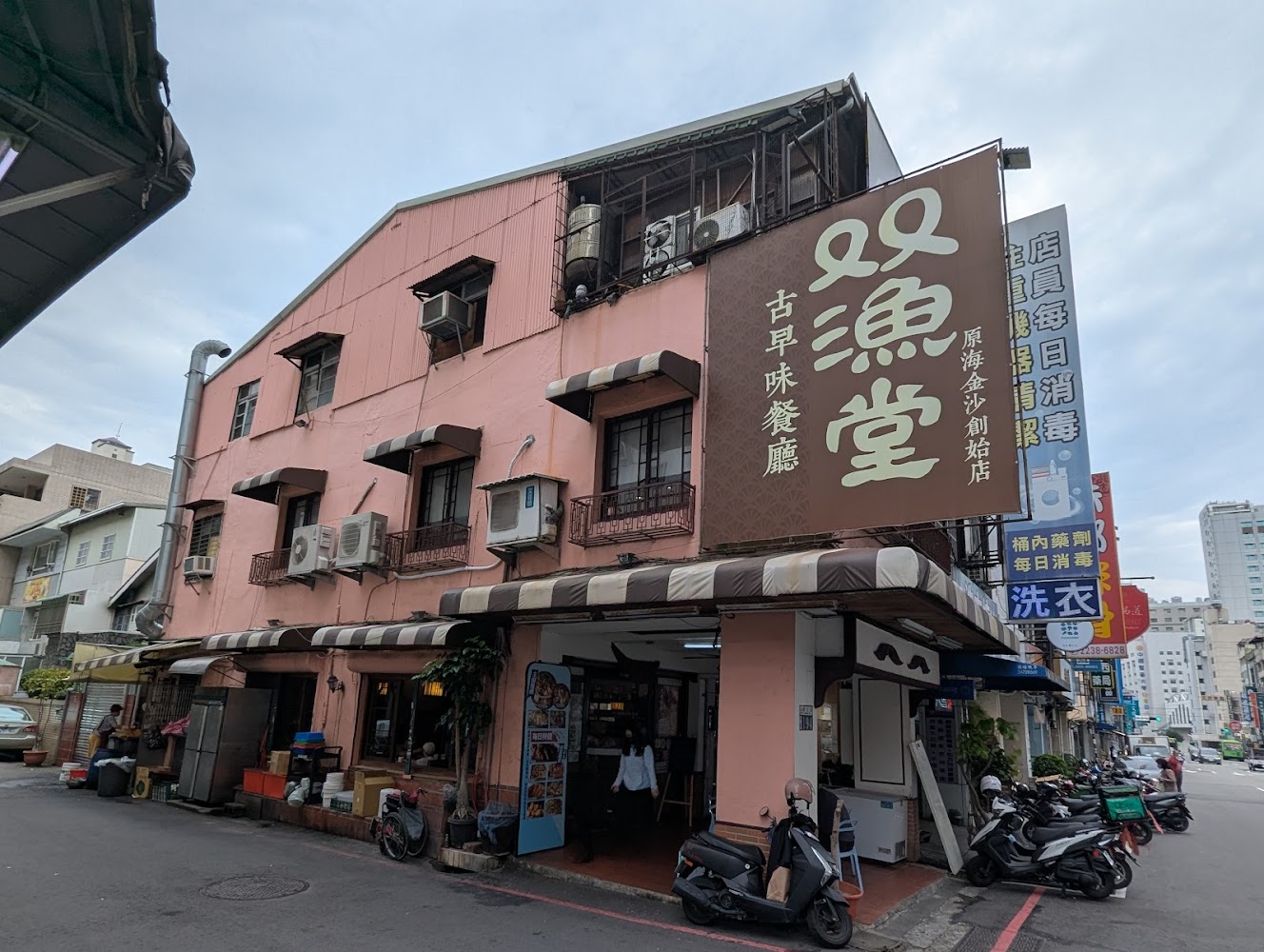 這張圖片主要是一家名為『雙漁堂』的餐廳，位於街角的粉紅色建築。一樓有騎樓和店面，外頭停有數輛機車。招牌顯示這裡主打古早味餐廳。