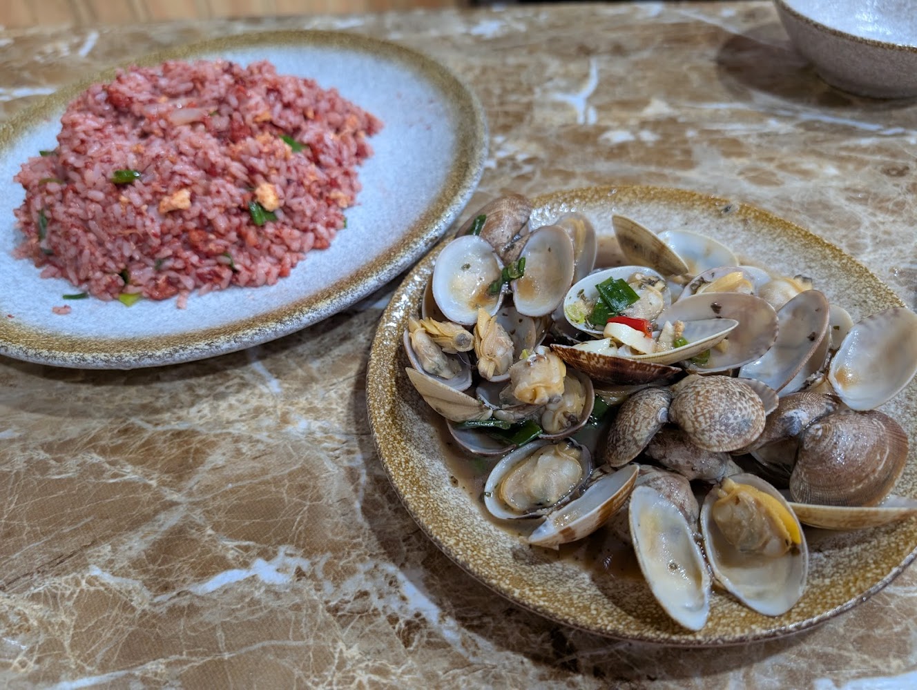 紅色炒飯與炒蛤蜊擺在桌面上色澤誘人