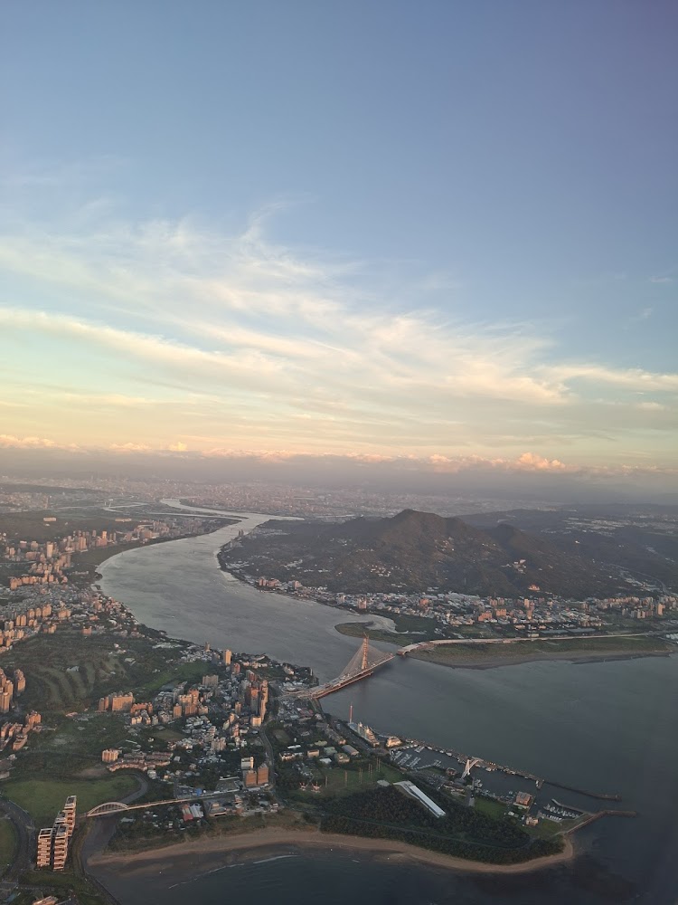 大河流經城市與山脈,河上有橋樑,附近有港口沙灘與城市建築