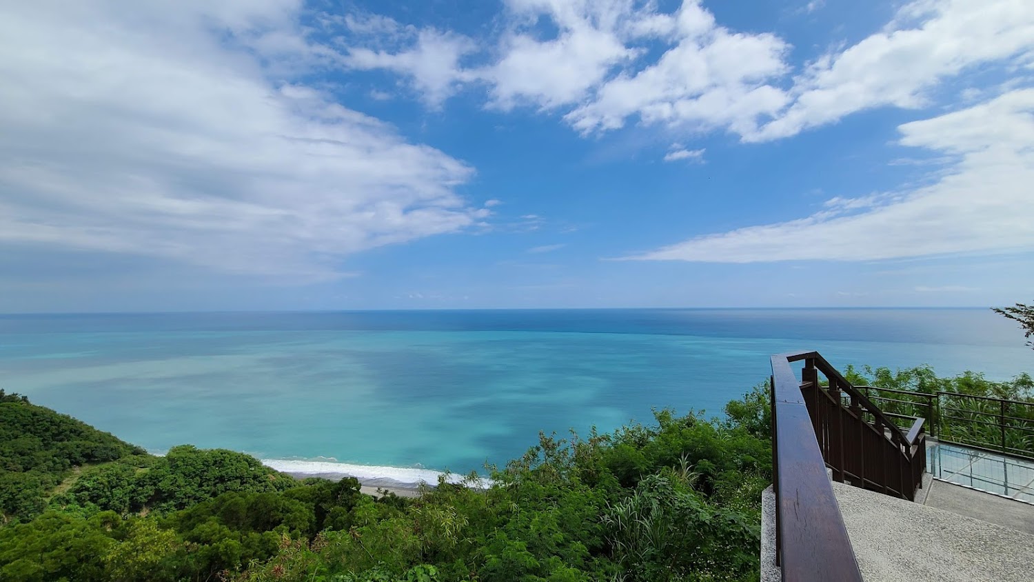 藍天白雲下的海景與山丘觀景平台