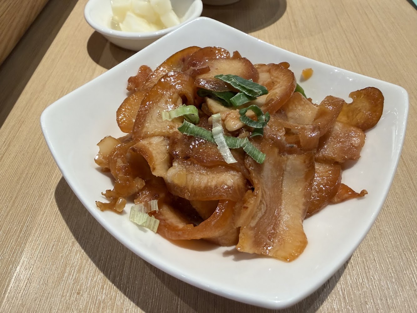 涼拌豬耳朵小菜，上面灑蔥花並附白色醃蘿蔔。