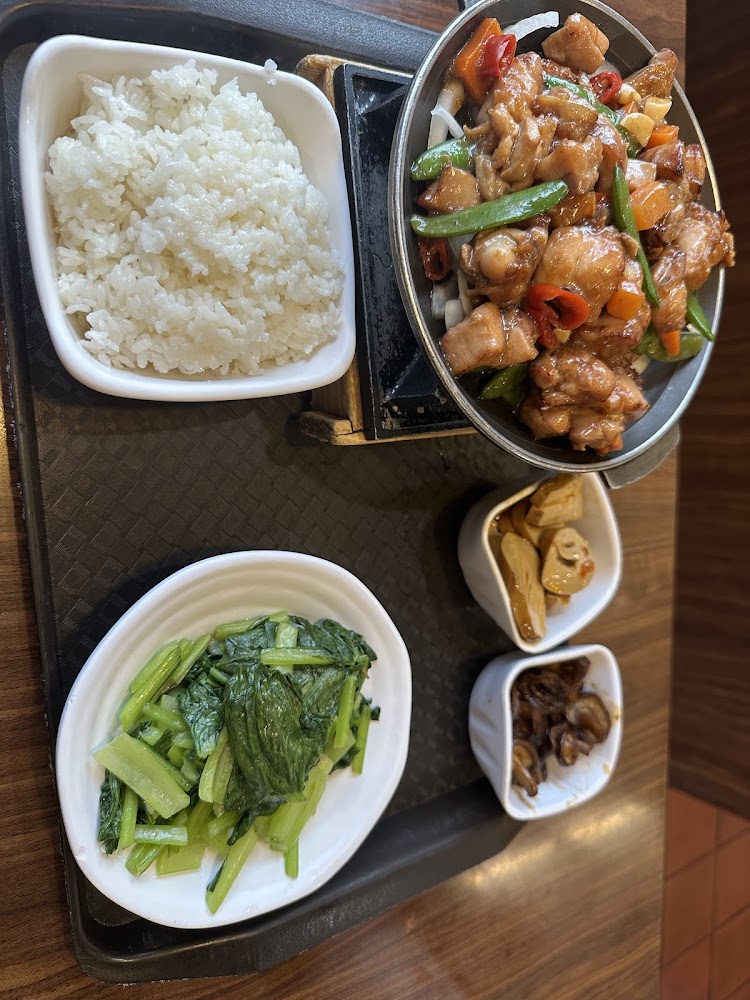 這張圖片展示了一份中式套餐，包括一碗白飯、一盤熱炒雞肉時蔬、一盤燙青菜，及兩款小菜，菜色豐富，營養均衡。