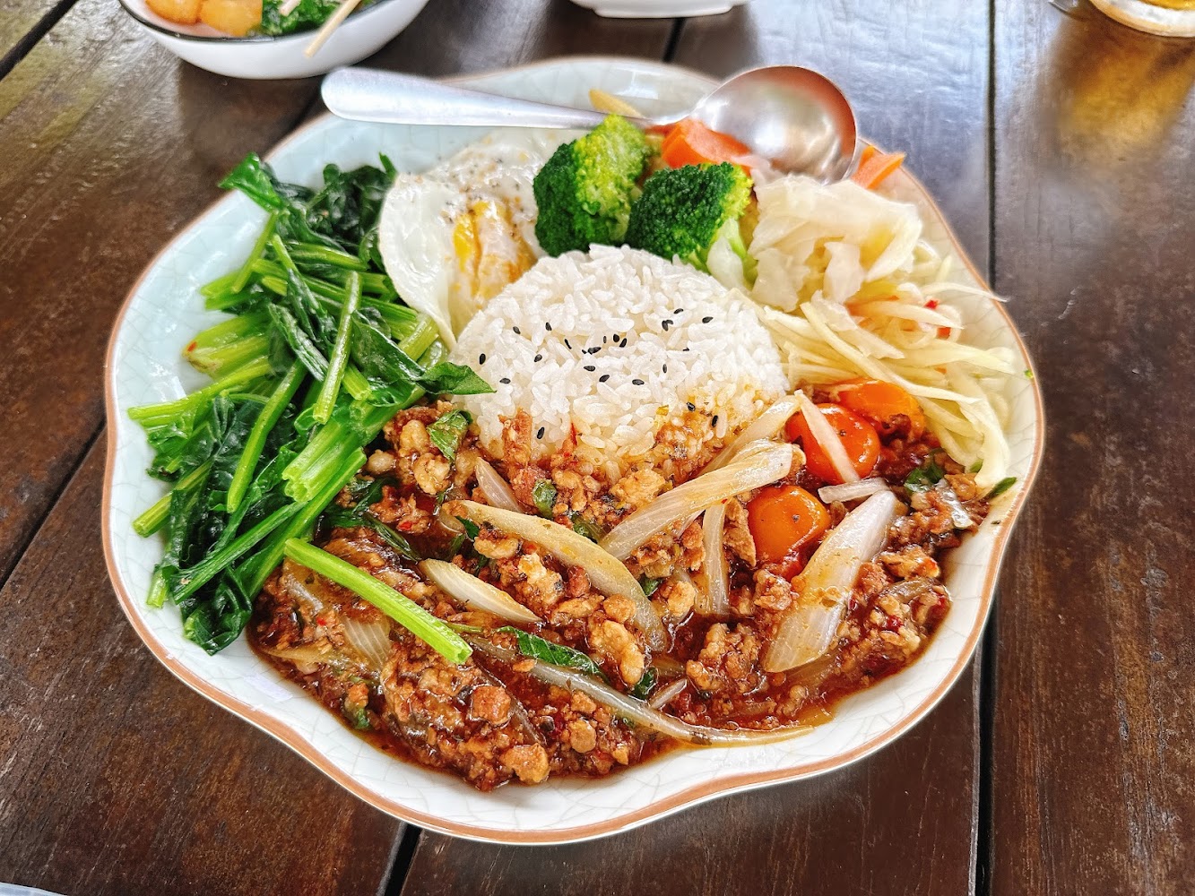 白飯搭配炒碎肉、洋蔥、蔬菜、青菜、花椰菜、煎蛋和涼拌菜的套餐