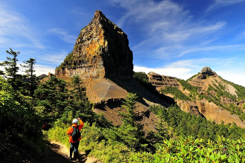 高聳壯麗的岩石山峰與登山者仰望山景