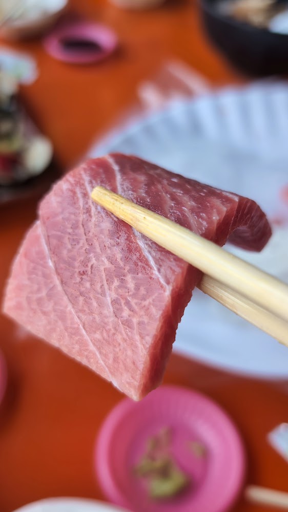筷子夾起一塊油花明顯的生魚片
