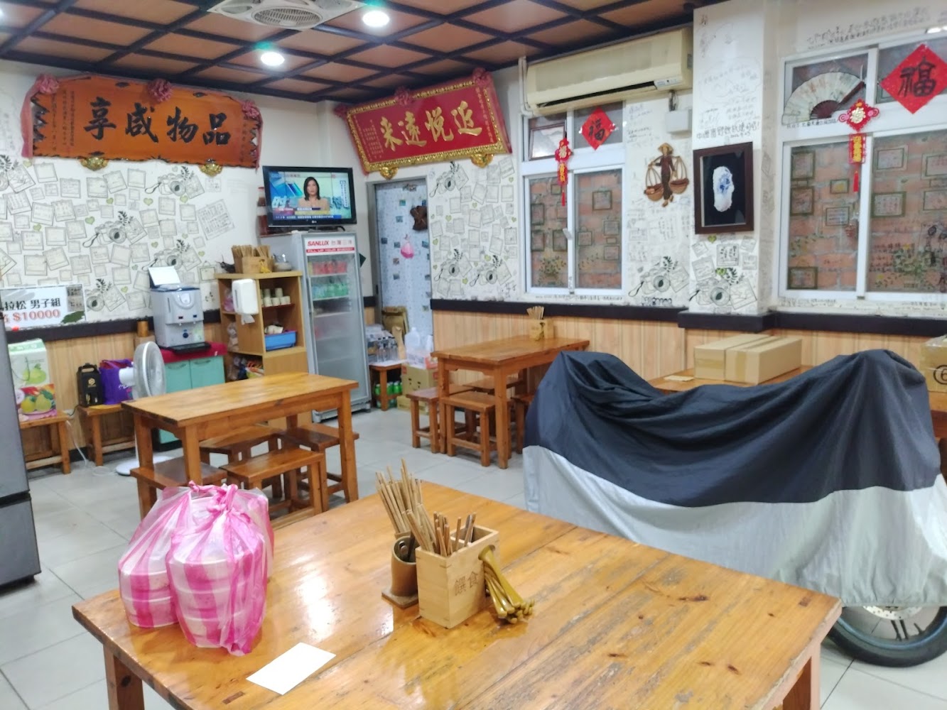 傳統小吃店內部，有木桌椅電視冰箱與飲水設備