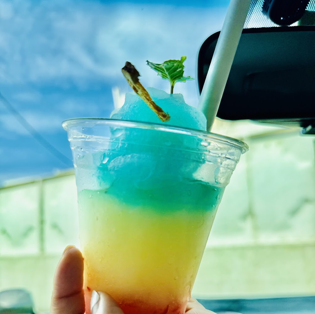 一杯彩虹色分層刨冰飲品，上方有薄荷葉裝飾