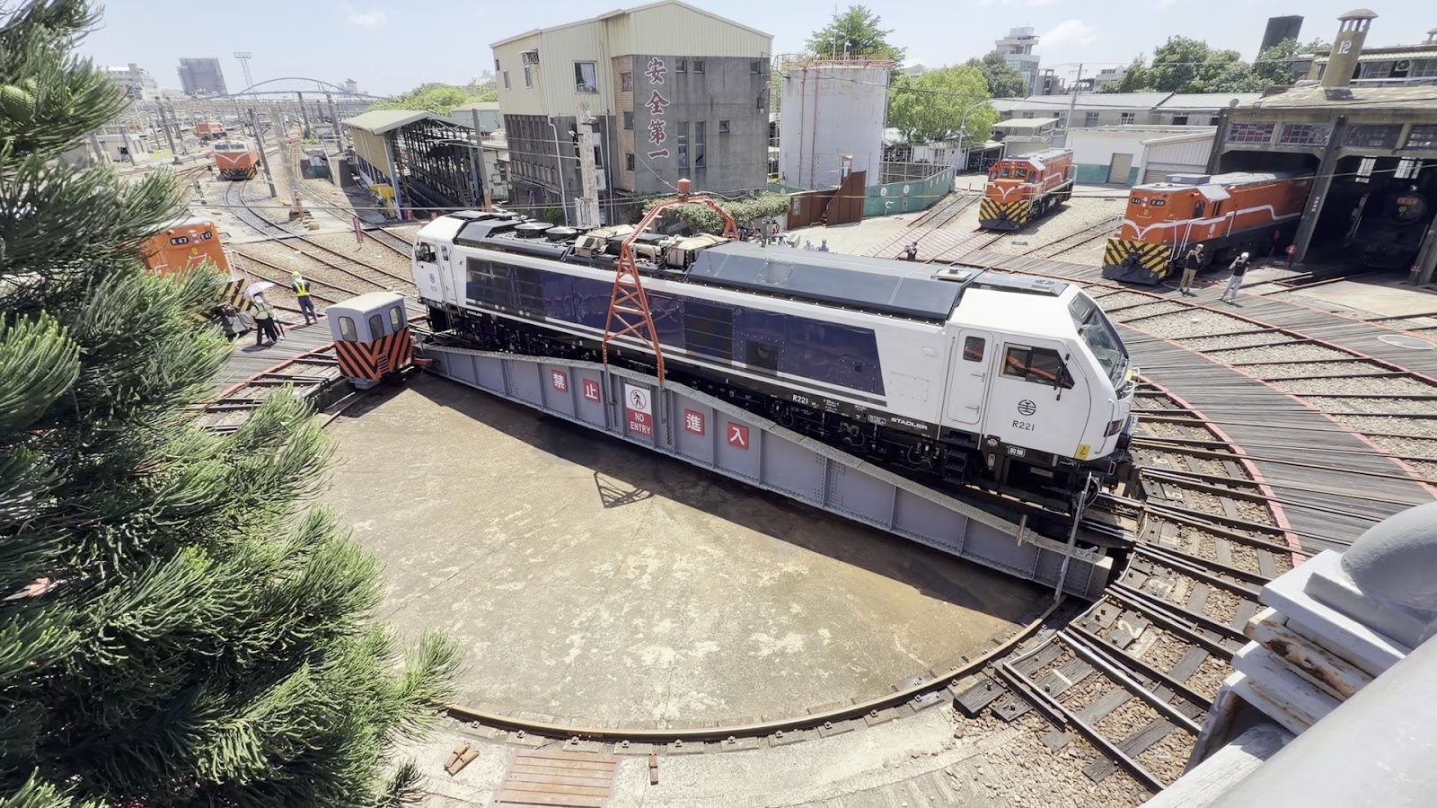 彰化扇形車庫轉車台，白色新型Stadler機車頭R221站在圓形轉車台上，橙色舊款柴油機車頭在背景