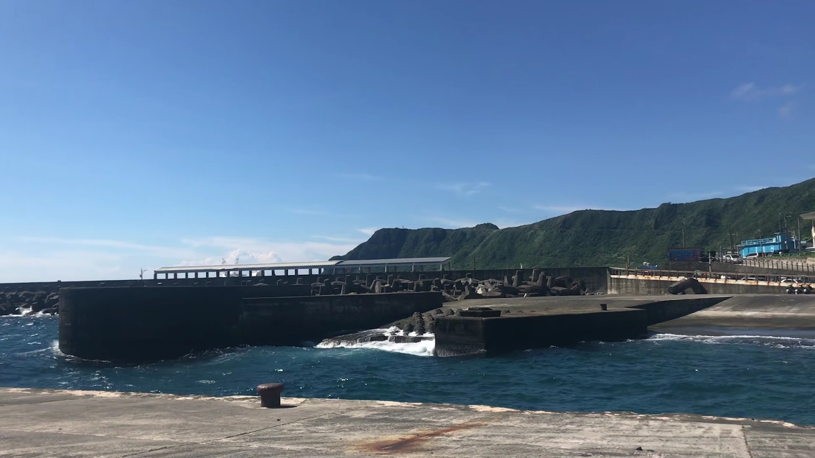 蘭嶼舊蘭嶼燈塔旁開元漁港碼頭黑色消波塊堤防蘭嶼翠綠山壁藍天