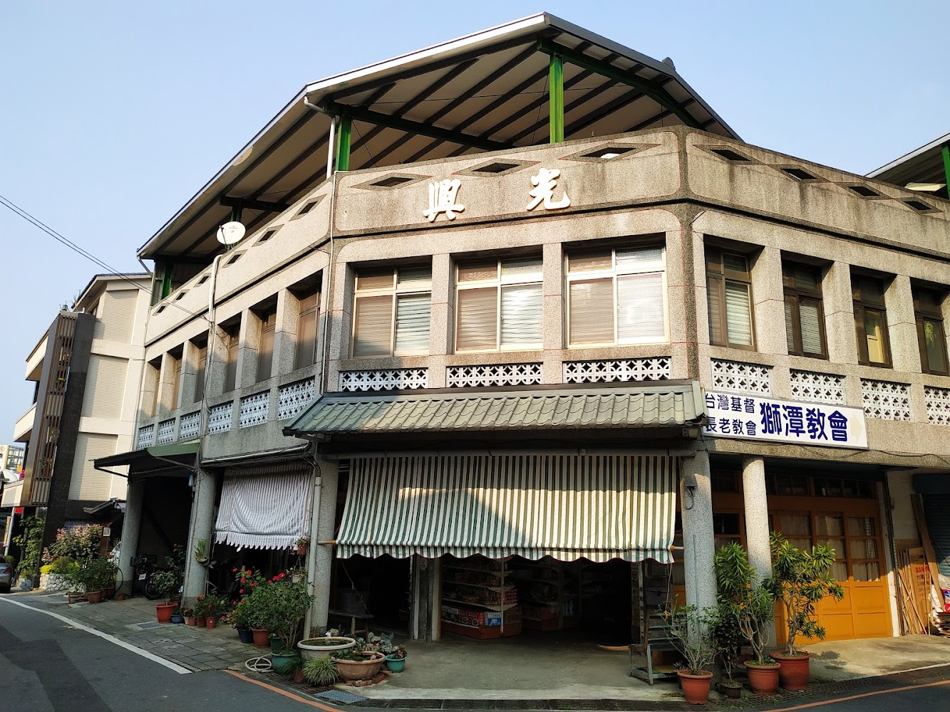 這張圖片主要是一棟帶有復古風格的台灣建築，外牆有光興字樣，並有遮陽棚與花草盆栽。