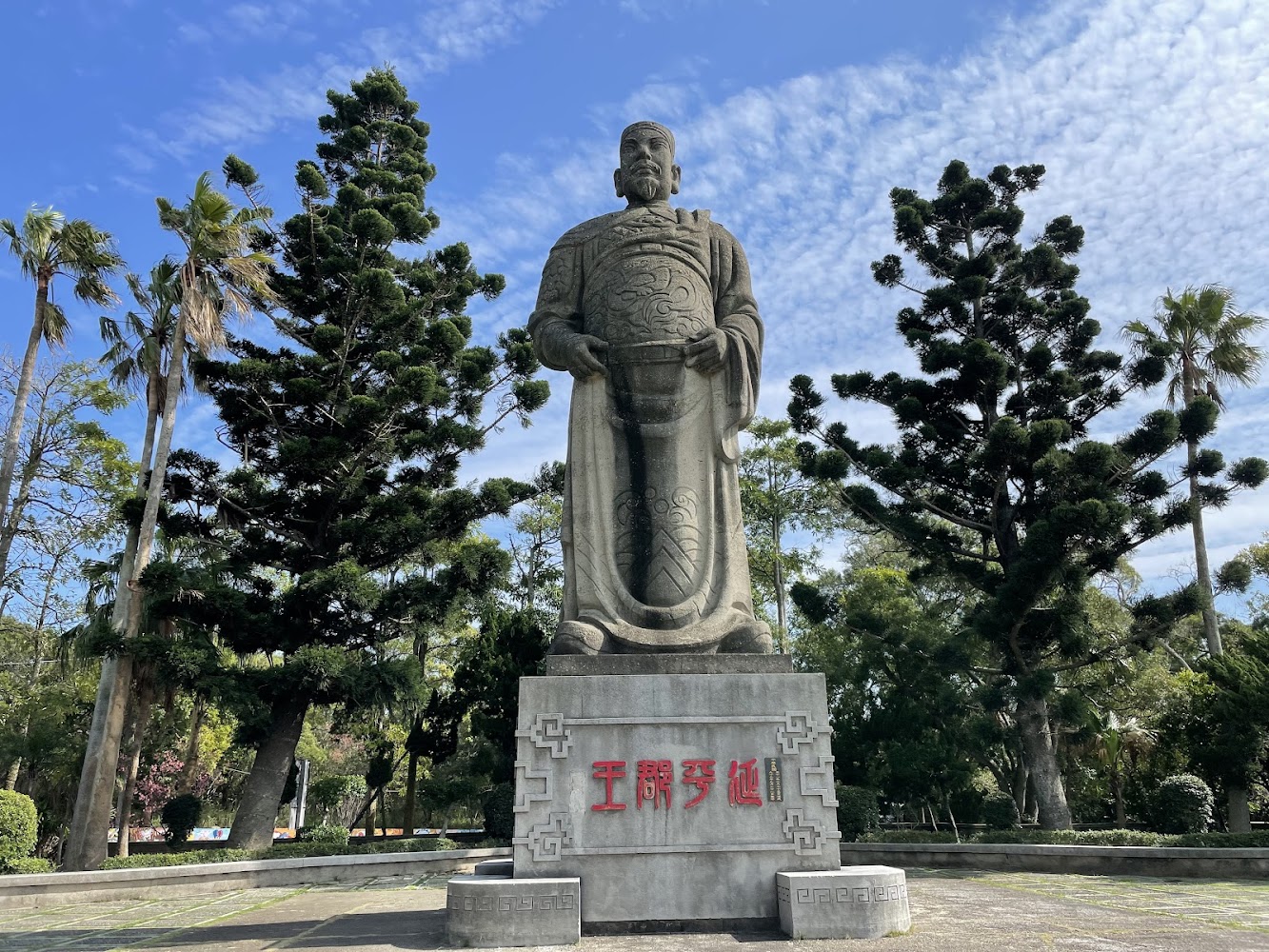 大型石雕人物雕像周圍有樹木與藍天氛圍莊嚴寧靜