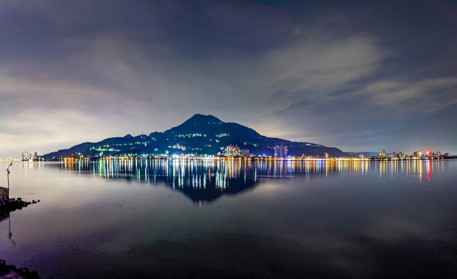 夜晚城市燈光與山景倒映在平靜水面上