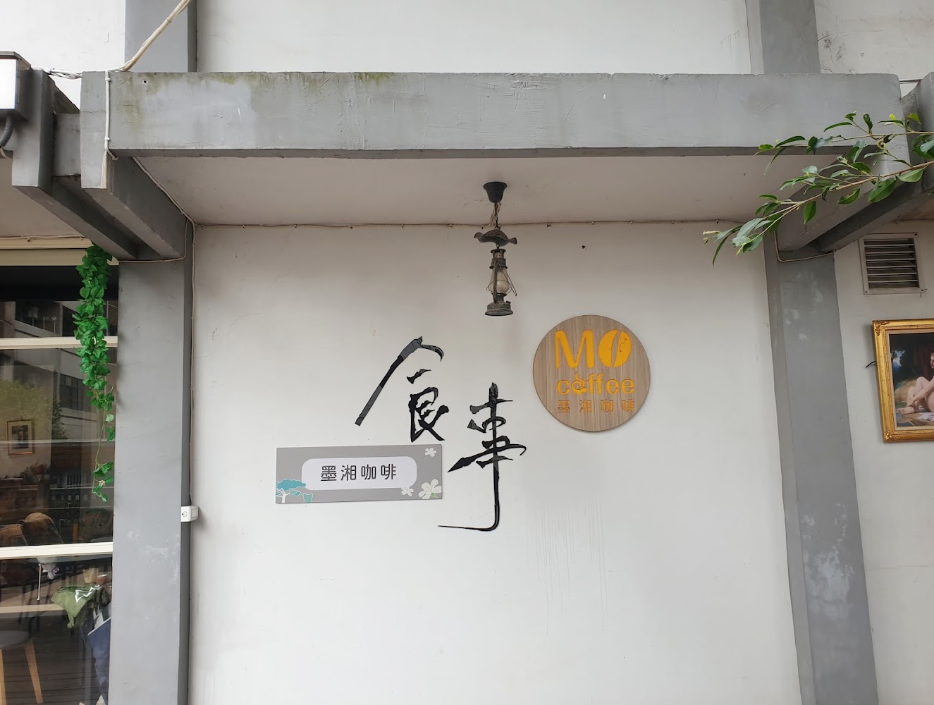 這張圖片主要顯示一家名為墨湘咖啡的咖啡館外牆，有招牌和燈飾，風格簡約。