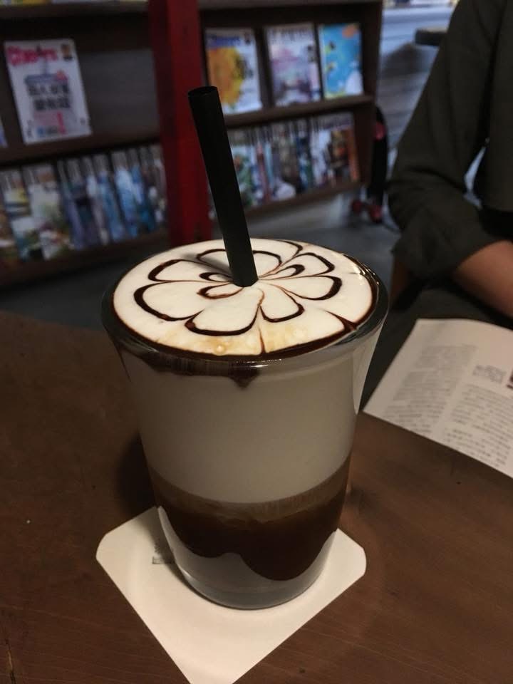 小曼咖啡店拉花拿鐵與書架背景