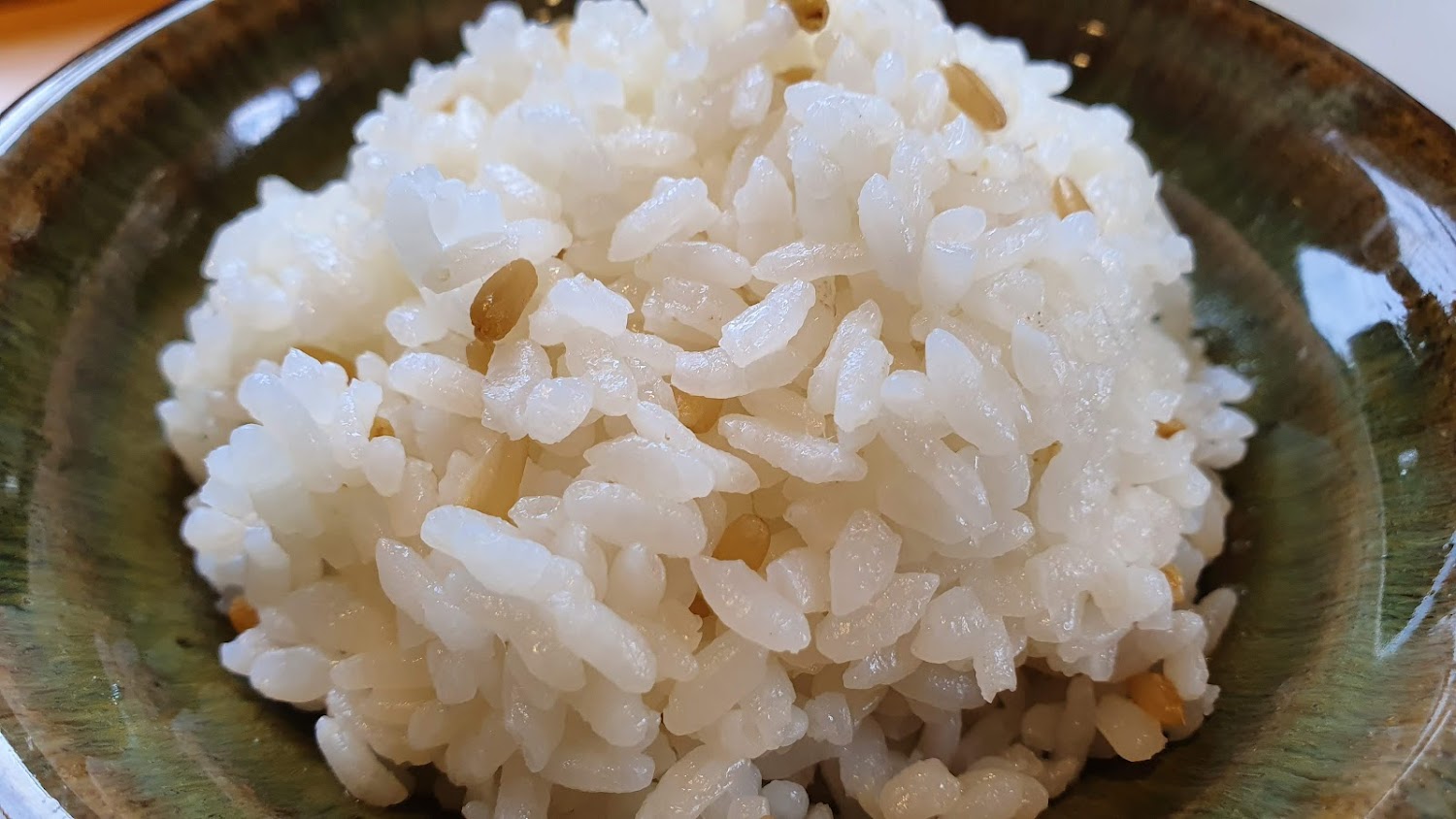 深色陶碗盛裝白飯與少量糙米，米飯粒粒分明