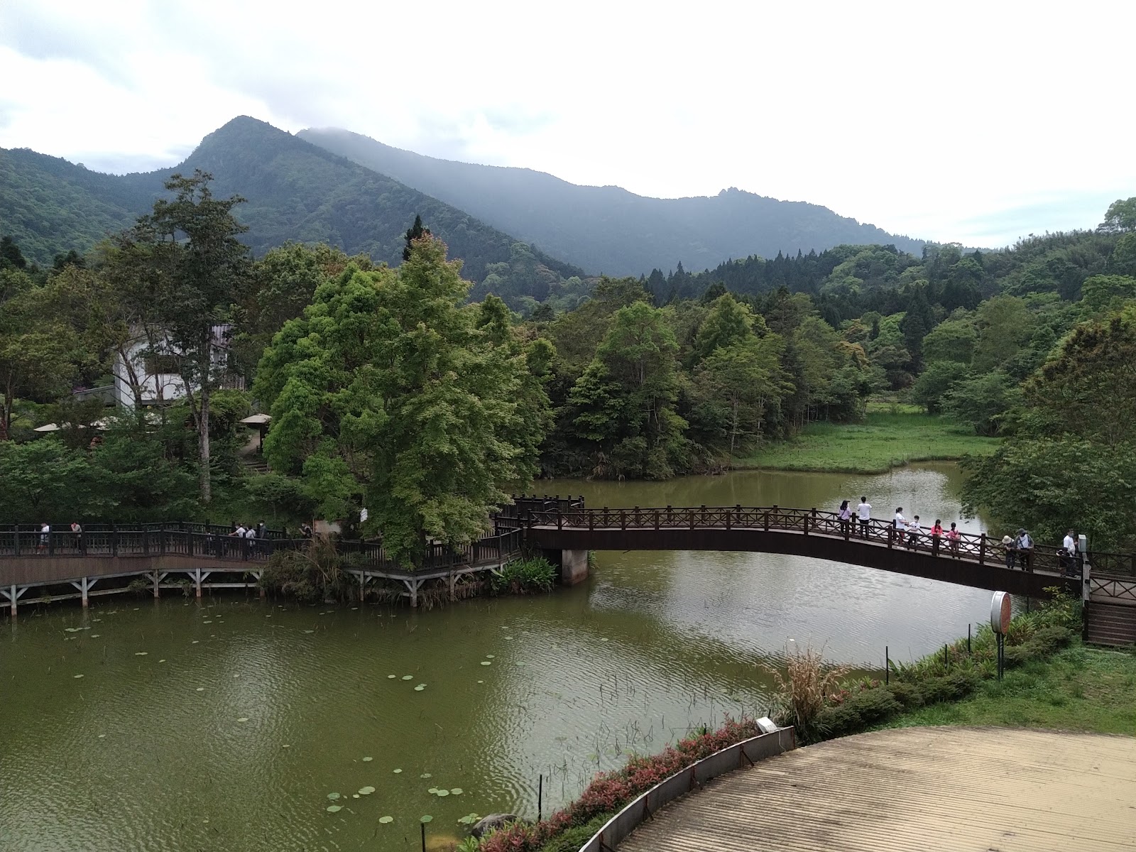向天湖全景，弧形木棧橋，遊客漫步，雲霧山脈