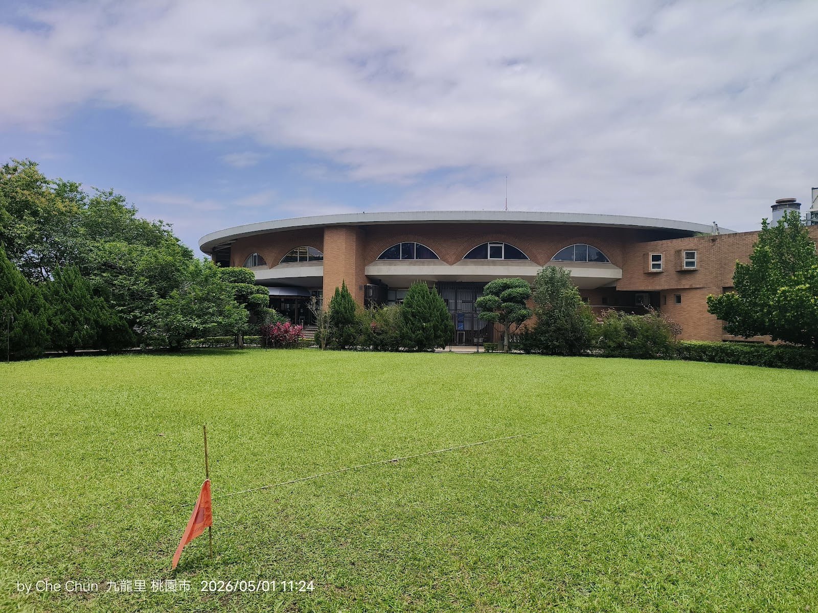 桃園悅華大酒店圓形建築外觀正面，綠草坪與高爾夫旗