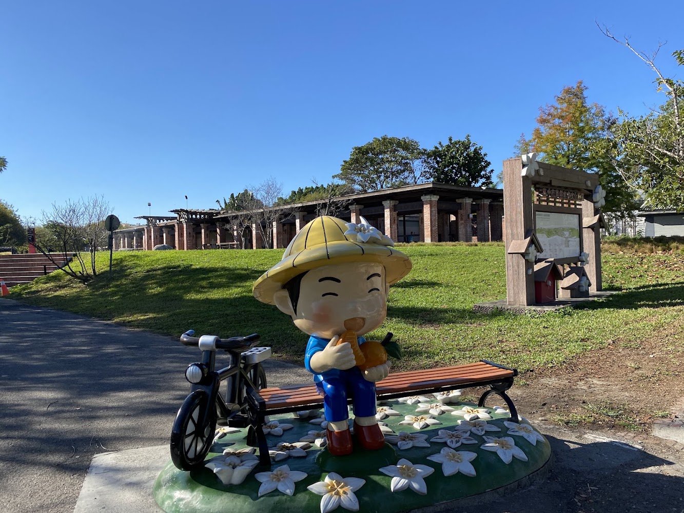 可愛小孩雕像坐在長凳旁有腳踏車與草地