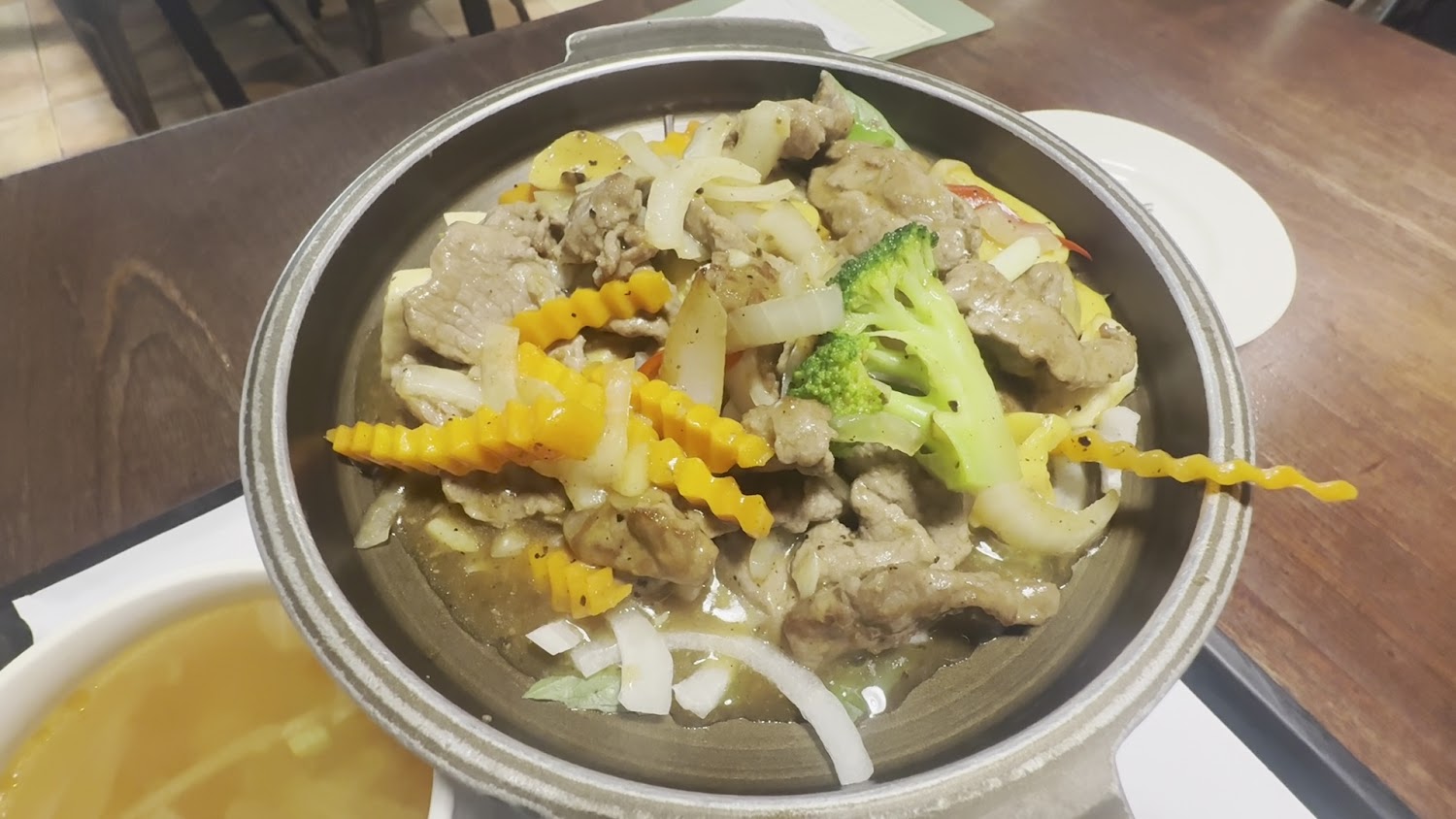 這張圖片主要是一鍋熱炒牛肉，有洋蔥、胡蘿蔔、馬鈴薯和花椰菜等蔬菜，搭配肉片，看起來香氣四溢又營養均衡。