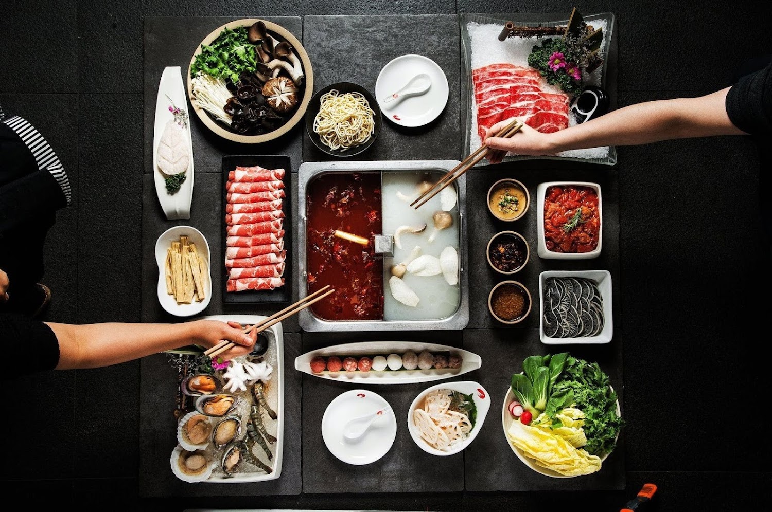 一大桌鴛鴦鍋火鍋食材，有牛肉海鮮丸子蔬菜與麵類