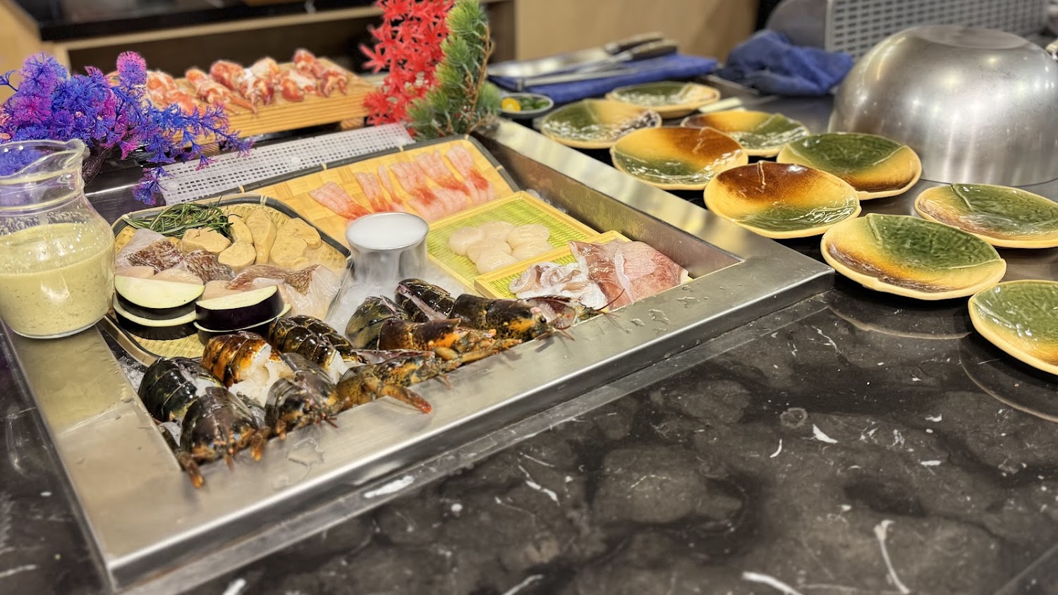 料理檯上展示龍蝦、干貝、魚片及肉品等新鮮海鮮食材