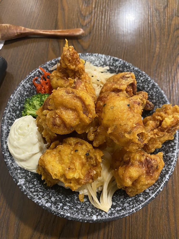 這張圖片主要呈現一盤炸物，外皮金黃酥脆，旁邊有美乃滋、花椰菜和醃漬蔬菜作為配料，整體擺盤豐富，看起來十分美味。