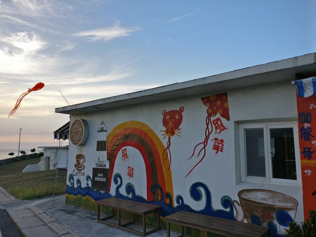 彩繪咖啡店外牆有彩虹風箏燈塔圖案與草地海岸