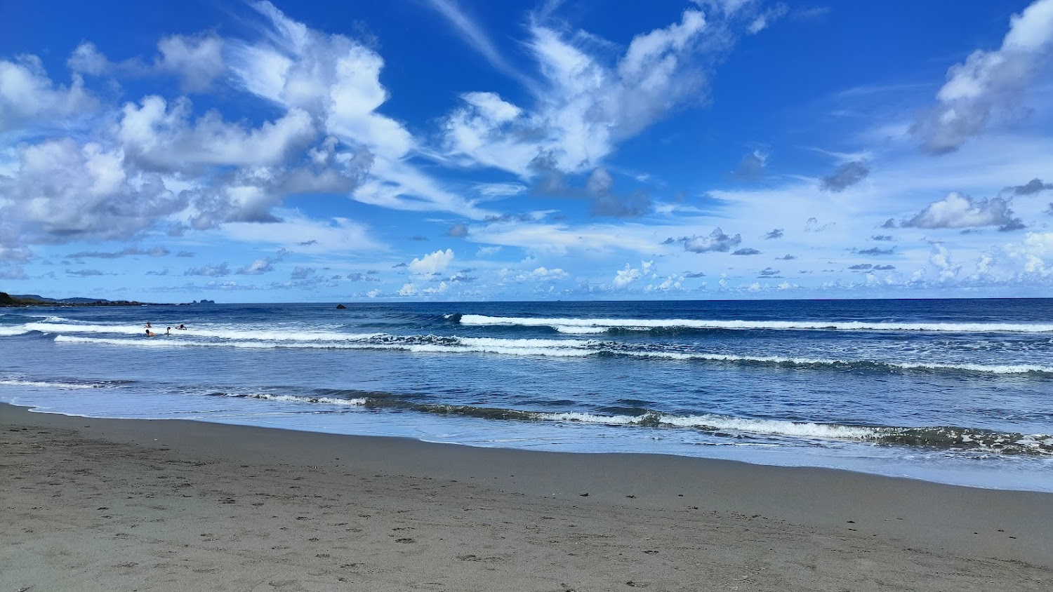 大片海灘與浪花、旅人在海中玩水